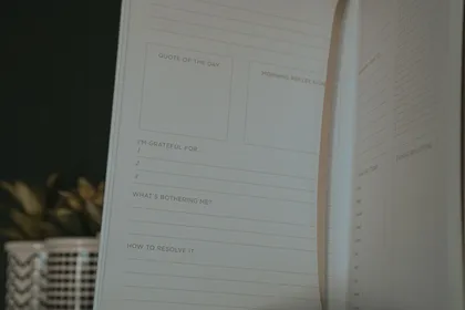 An open gratitude journal with prompts for reflection, beside a small plant